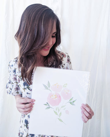 Hillary Proctor holding one of her watercolor paintings